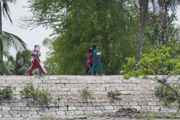 Meninas caminham por um muro de contenção no distrito de Satkhira, em Bangladesh. A altura das barreiras deverá ser elevada para proteger as populações costeiras do aumento das tempestades e dos ciclones. Foto: Rafiqul Islam/IPS