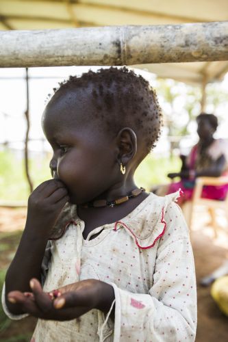 Uma menina come um sanduíche no novo abrigo de sua família, no acampamento Proteção dos Civis III, perto da Casa da ONU, em Juba, capital do Sudão do Sul. Foto: UN Photo/JC McIlwaine